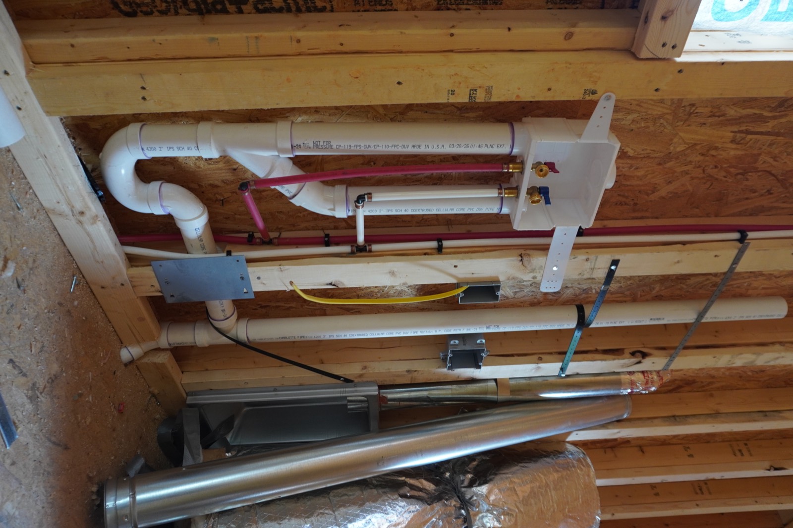 Washing-machine outlet box with PEX supply lines and PVC drain piping roughed into a framed wall