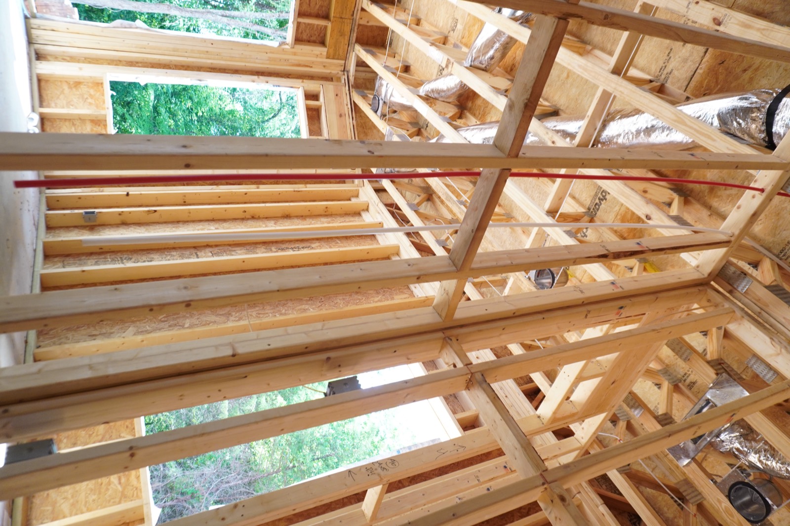Framed interior with insulated duct runs overhead on a job in progress