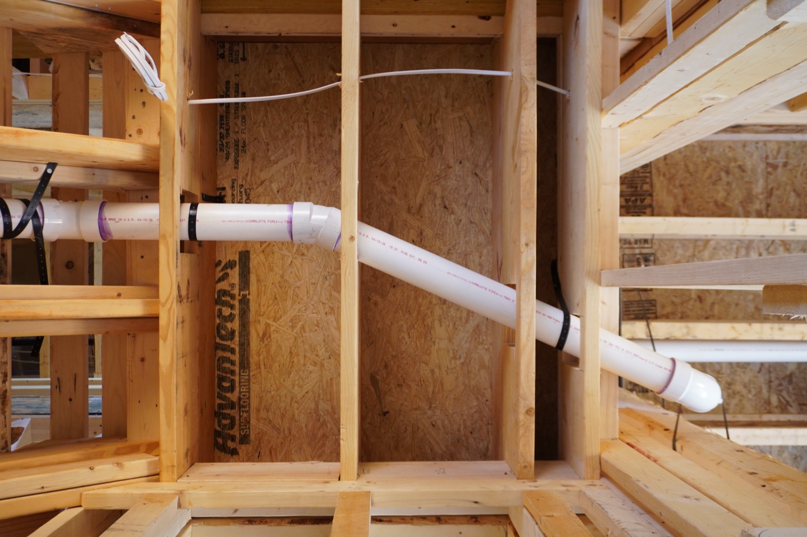 PVC drain line run through floor framing on a job in progress